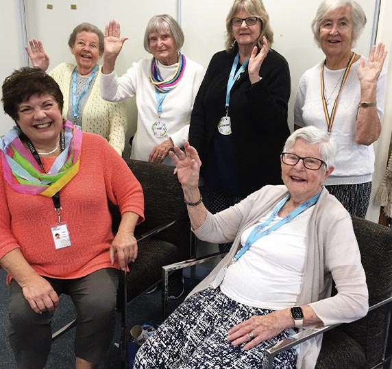Group of six older ladies happily waving hello